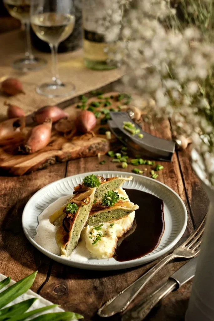 Maultaschen auf Kartoffelbrei mit heller und dunkler Soße im rustikalen Landhausstil, fotografiert von Studio Visionelle.